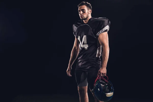 athletic american football player in black uniform isolated on black