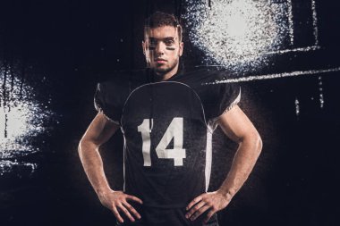 view of american football player looking at camera on black through wet glass clipart