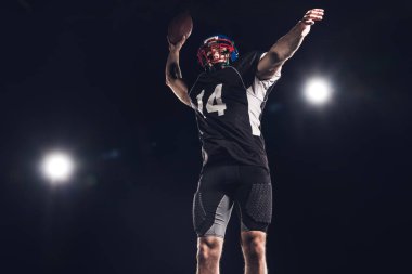 bottom view of american football player throwing ball under spotlights on black clipart