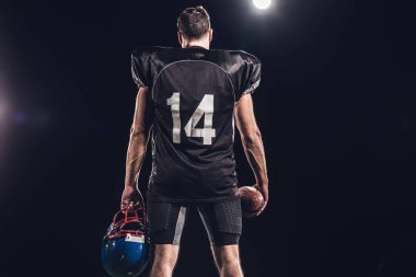 Amerikan futbolu oyuncusu topu ve kask spot altında siyah dikiz