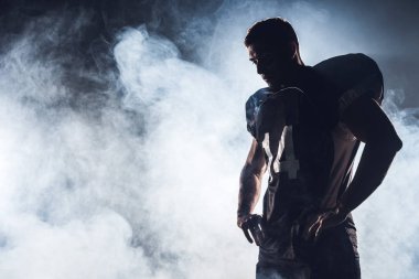dark silhouette of thoughtful american football player looking down against white smoke clipart