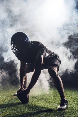 silhouette of athletic american football player in star position against white smoke clipart