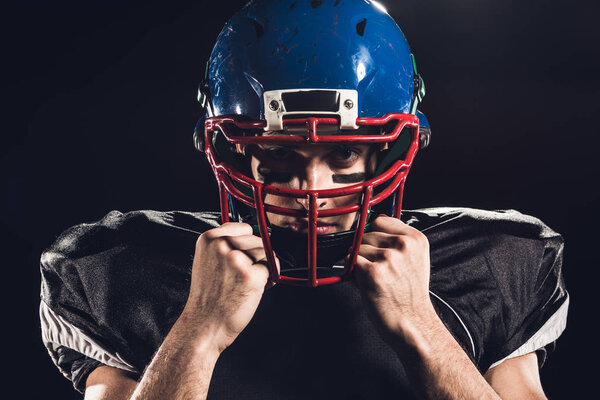 close-up portrait of american football player in helmet looking at camera isolated on black