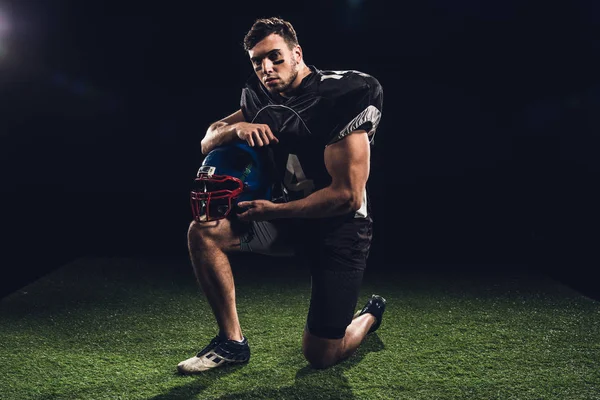 Çim Siyah Kask Ile Diz Üzerinde Duran Amerikan Futbolu Oyuncusu — Stok fotoğraf