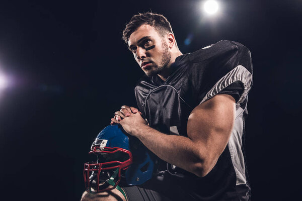 Американский футболист в шлеме смотрит в сторону в центре внимания на черный
