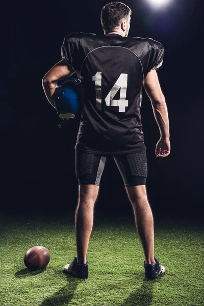 Amerikan futbolu oyuncusu ile kask ayakta yeşil çimenlerin üzerinde siyah dikiz