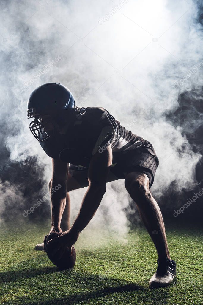 silhouette of athletic american football player in star position against white smoke