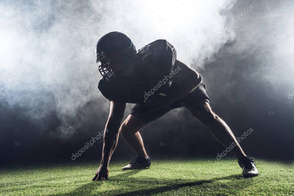 silhouette of american football player in star position against white smoke