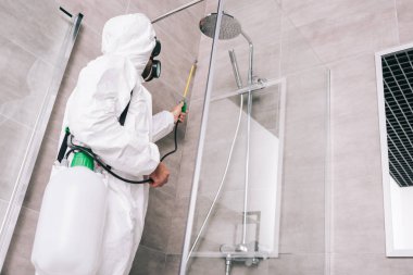 low angle view of pest control worker spraying pesticides with sprayer in bathroom clipart