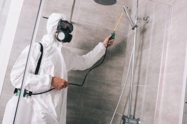 pest control worker spraying pesticides with sprayer in bathroom clipart