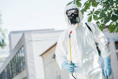 low angle view of pest control worker standing with sprayer  clipart