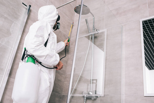 низкий угол зрения вредителя рабочий распыления пестицидов с распылителем в ванной комнате

