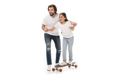 Baba küçük kızı beyaz izole kaykay üzerinde paten yardım