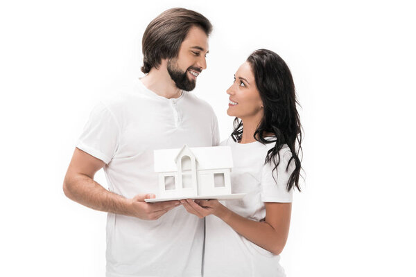portrait of smiling couple with house model isolated on white