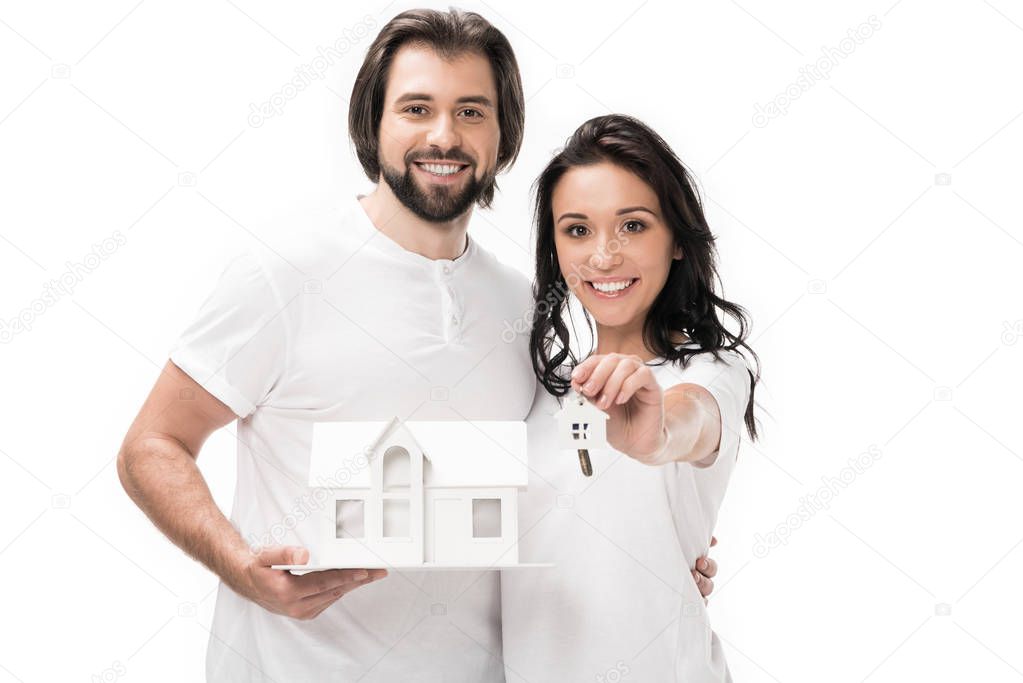 portrait of smiling couple with house model and keys isolated on white
