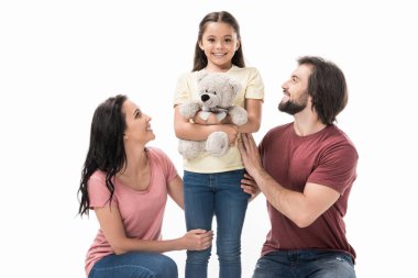 smiling parents and daughter with teddy bear isolated on white clipart