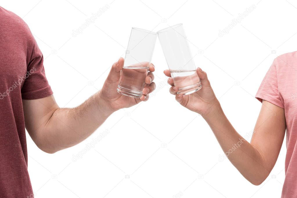 partial view of couple clinking glasses of water isolated on white