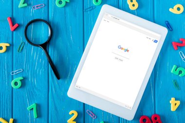 google web sitesi ile dijital tablet ekranı, Büyüteç, ataç ve mavi ahşap arka plan üzerinde renkli numaraları yukarıdan 