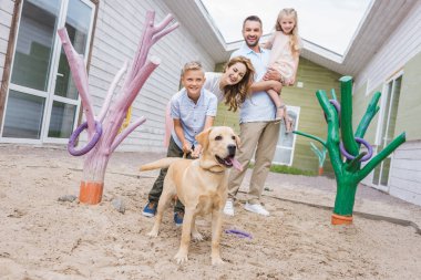 smiling parents and children standing with adopted labrador at animals shelter clipart