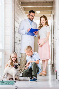 children and mother choosing pug dog for adoption at animals shelter clipart
