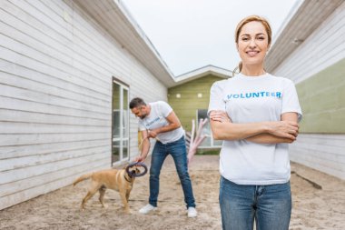 volunteer of animals shelter playing with labrador dog, woman looking at camera clipart