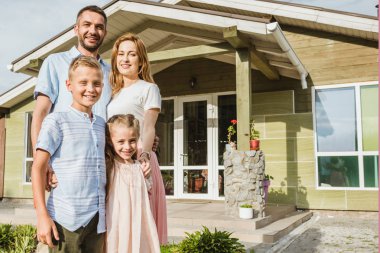 smiling parents and children standing in front of house clipart