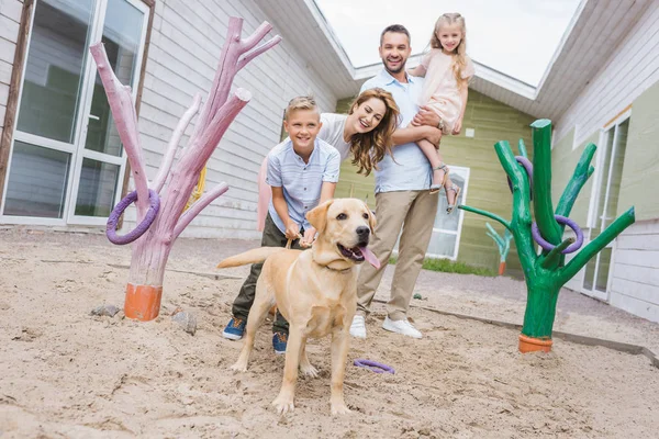 smiling parents and children standing with adopted labrador at animals shelter