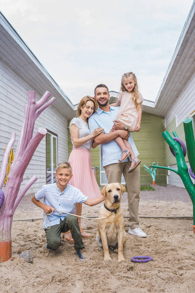 happy parents and children standing with adopted labrador dog at animals shelter