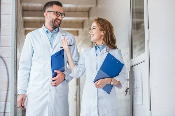 Uśmiechający Się Weterynarze Białych Kitlach Chodzenie Schowki Klinice Weterynaryjnej Patrząc — Zdjęcie stockowe