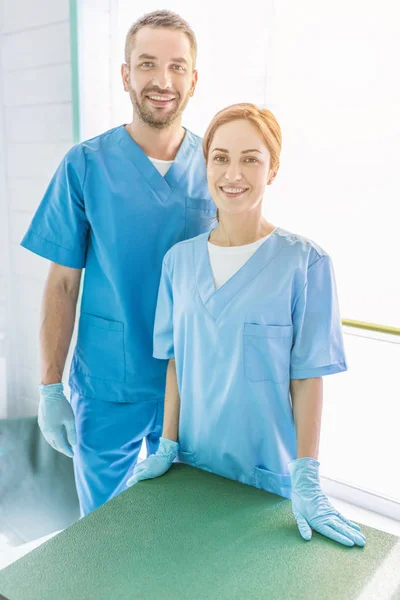 Sonriendo Dos Veterinarios Pie Uniforme Mirando Cámara Clínica Veterinaria —  Fotos de Stock