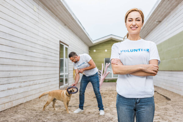 volunteer of animals shelter playing with labrador dog, woman looking at camera