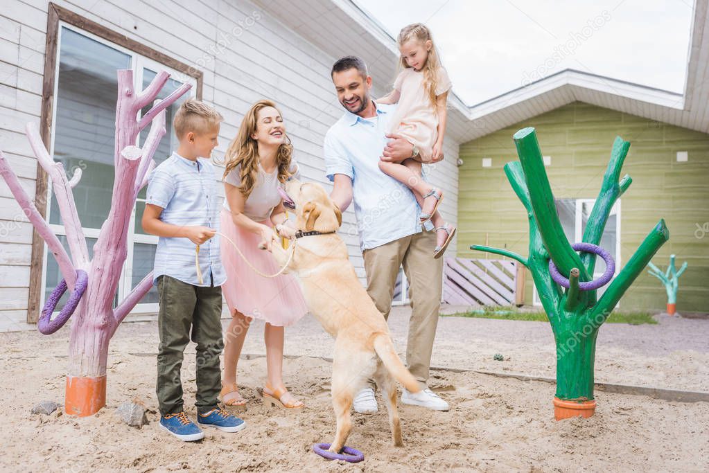 parents and children playing with adopted labrador at animals shelter