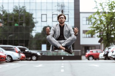 lotus poz havada yüzen ve park yerinde meditasyon yakışıklı genç işadamı