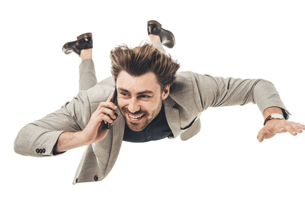 happy young businessman talking by phone while falling isolated on white