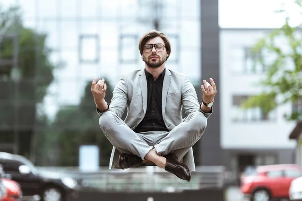魅力的な青年実業家ロータス ポーズで空気中に浮遊し 駐車場で瞑想 — ストック写真