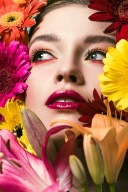 close-up portrait of attractive young woman surrounded with various flowers looking up clipart