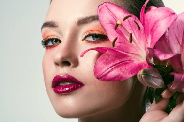 close-up portrait of beautiful young woman with stylish makeup and pink lilium flowers isolated on white clipart