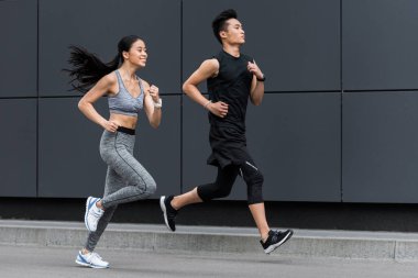 side view of asian sportsman and sportswoman running at city street  clipart