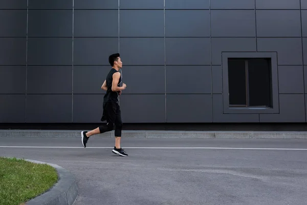 Zijaanzicht Van Jonge Aziatische Sportman Oortelefoons Lopen Bij Stad Straat — Stockfoto