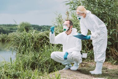 kadın bilim adamı bu durumda Pano test şişeye su örneği inceleyerek onun erkek arkadaşı iken yazma maske ve koruyucu giysi 
