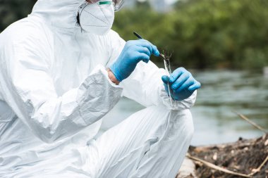 toprak örneği test şişesi açık havada cımbız tarafından koyarak maske ve koruyucu giysi içinde erkek bilim adamının kırpılmış görüntü 