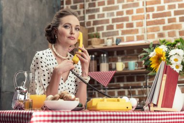 Mutfak vintage kablolu telefonla konuşurken kendinden emin yetişkin ev kadını