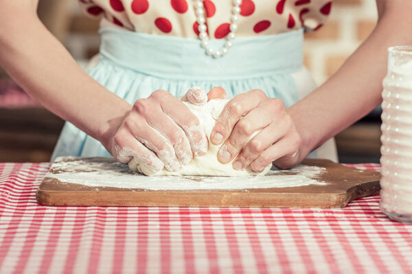 cropped shot of woman kneading dough with hands on wooden cuting board