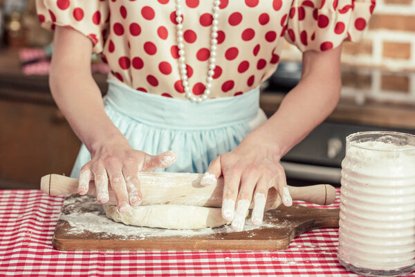 cropped shot of woman kneading dough with rolling pin at kitchen