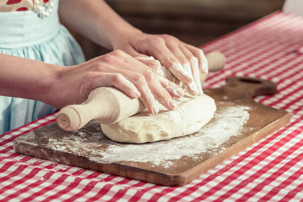 cropped shot of woman kneading dough with rolling pin