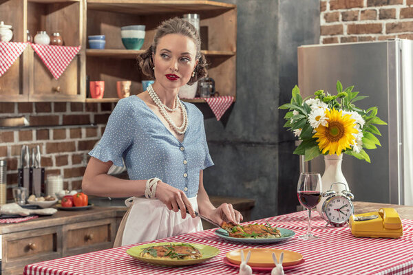 beautiful adult housewife cutting fresh mushroom cake and looking away at kitchen