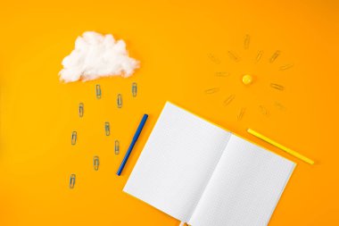 top view of blank notebook and cloud with sun made of paper clips and cotton on yellow clipart