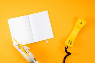 robot el vintage telefon ile sarı masa üstü boş not defterinde yazılı bardak kırpılmış