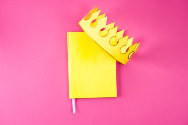 sarı defter kağıt taç ile üstten görünüm pembe üzerinde