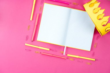 boş açılan defter ile aletleri ve kağıt taç üstten görünüm pembe üzerinde